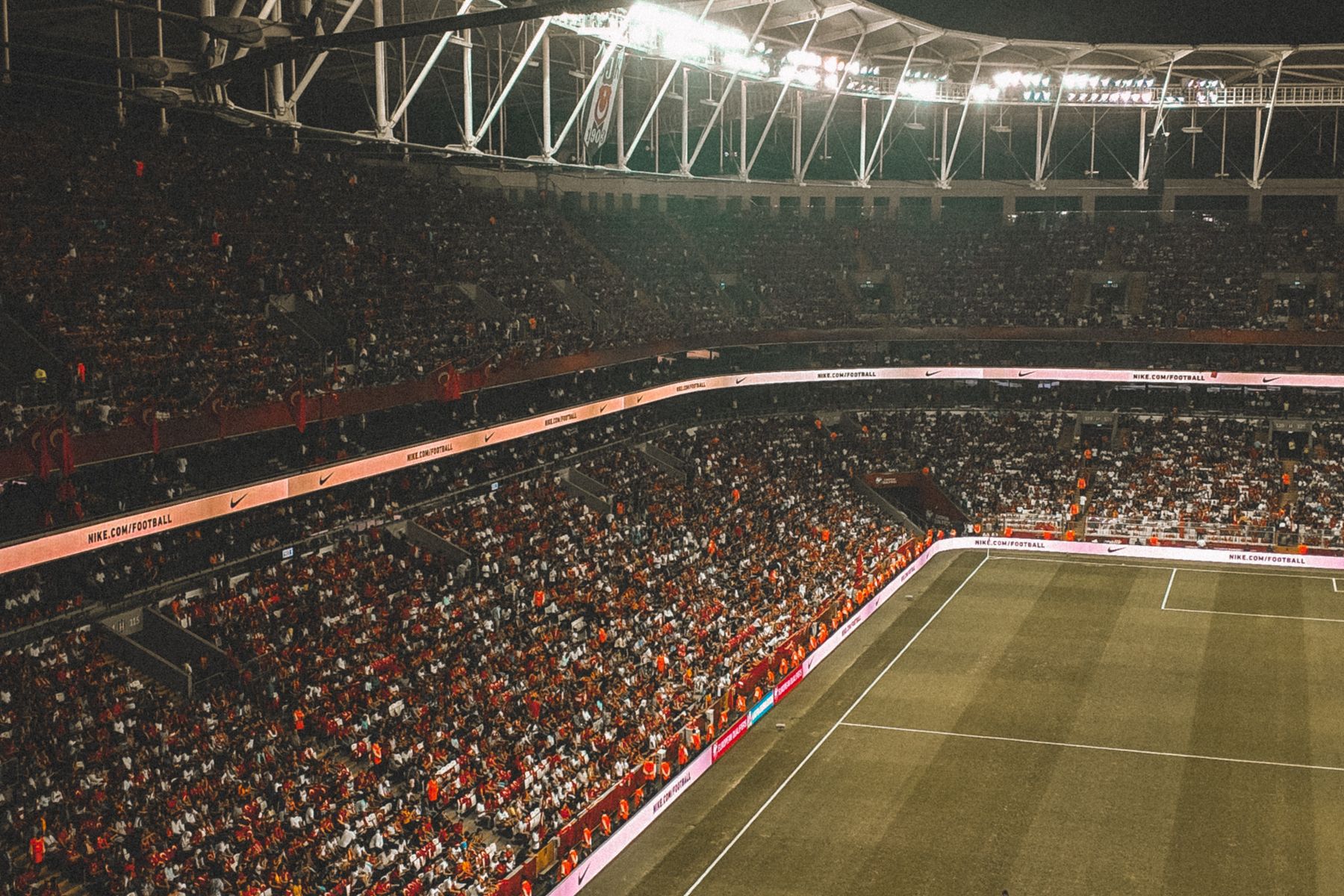 Estadio de fútbol lleno de noche, con la cancha iluminada.